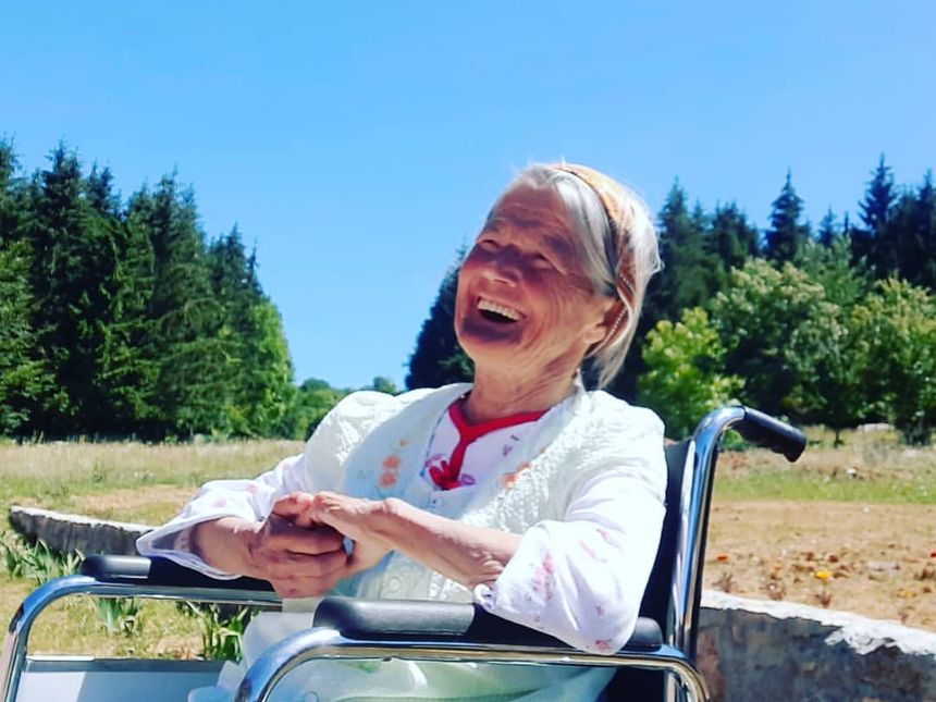 Nasmijana stanarka napolju, iza nje šuma i vedro nebo