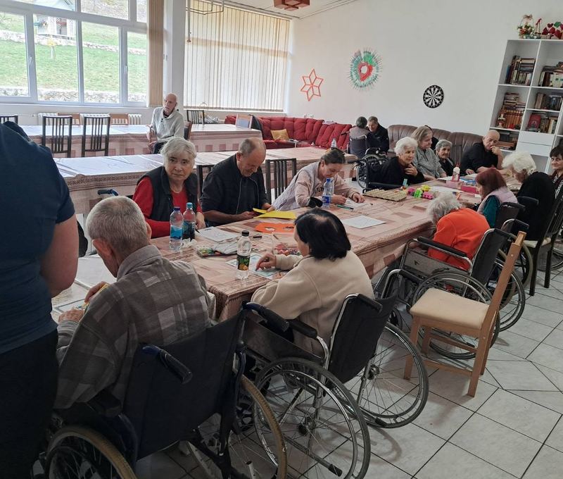 Zajednička sala sa velikim prozorima, stanari za stolovima crtaju